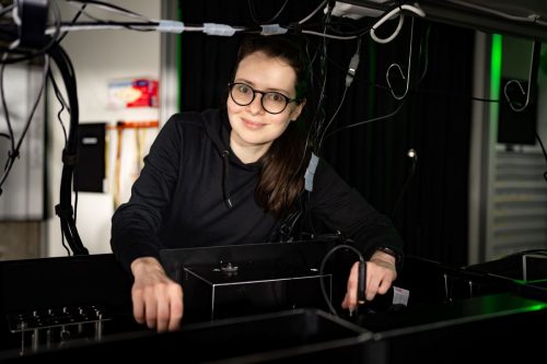 Lyuba Amitonova stands in a lab next to an optical experiment setup. Photo: Ivar Pel